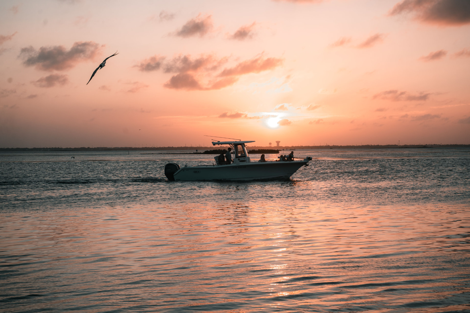 Westwind Waterman charter boat silhouetted against a golden Gulf Coast sunset with guests aboard